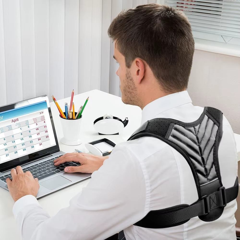 Homme porte correcteur de posture dos noir devant l'ordinateur