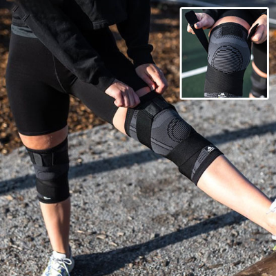 Une femme ajuste la genouillère sport - Avec sangle -FitConfort