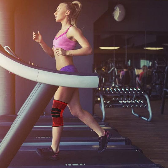 Femme cours sur un tapis de course dans une salle de sport avec les genouillere rotule - Rouge 