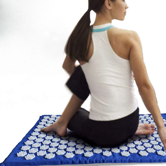 Femme s'assoit sur le tapis d'acupression - Fleur de lotus bleu 