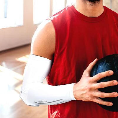 Un homme avec le manchon de compression bras - RegenArm tien un ballon de basketball dans un gym 