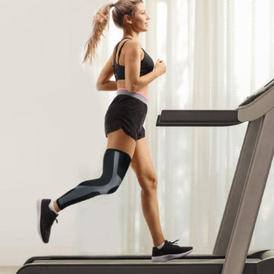 Une femme court sur le tapis roulant avec ses manchons de compression - PulseFit aux genoux