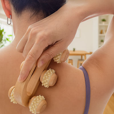 Une femme masse ses épaules avec le rouleau massage - Énergie Bois 